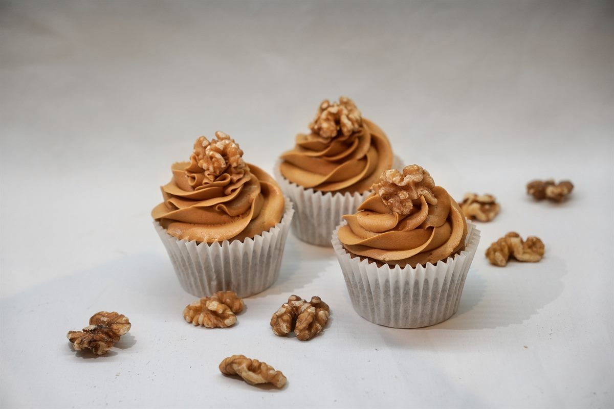 Three coffee cupcakes piped with coffee buttercream swirls, each topped with a walnut half