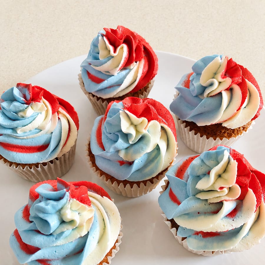 Six cupcakes topped with red, white and blue swirled buttercream