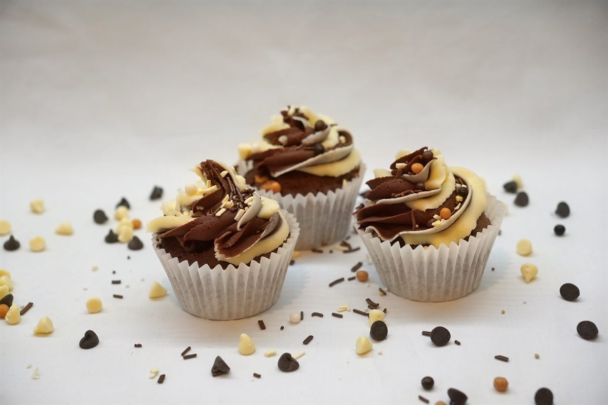 Three chocolate cupcakes piped with ribbons of dark, milk and white chocolate buttercream